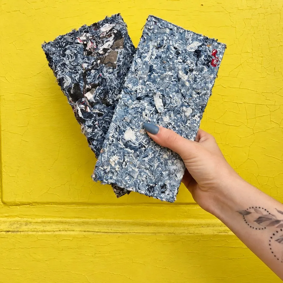 Una mano sostiene dos paneles Requecho en tonos azules y blancos contra una puerta pintada de amarillo.